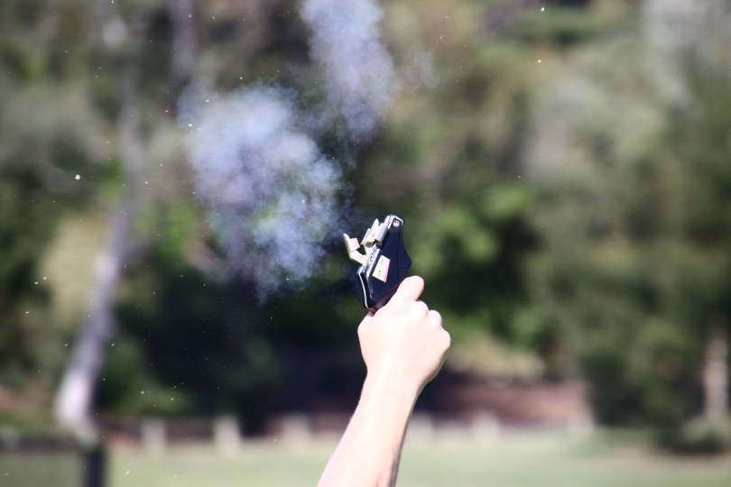 An athletics starter pistol just after firing, with an eplosive cloud