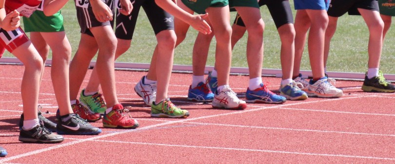 9 sets of feet lined up behind a start line